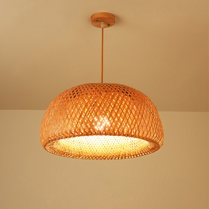 A hand-woven rattan cocoon pendant light hanging over a bed dressed in undyed linen, casting warm, dappled light in a sun-bleached coastal bedroom